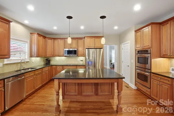 a kitchen with kitchen island granite countertop a stove a sink a refrigerator and cabinets