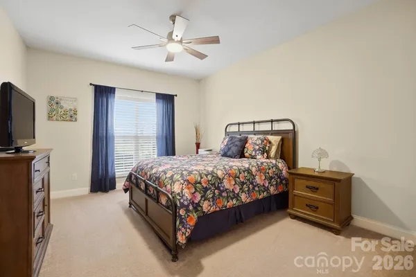a bedroom with a bed a mirror on dresser and a chandelier