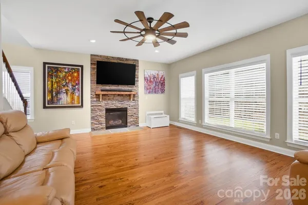 a view of a livingroom with a flat screen tv ceiling fan and fireplace
