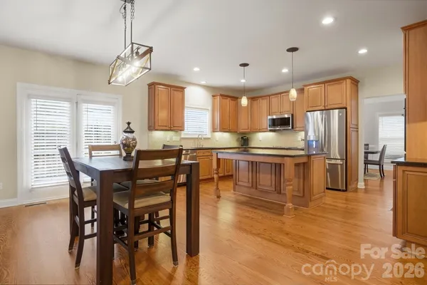 a kitchen with stainless steel appliances granite countertop a refrigerator a stove a kitchen island with a dining table and chairs