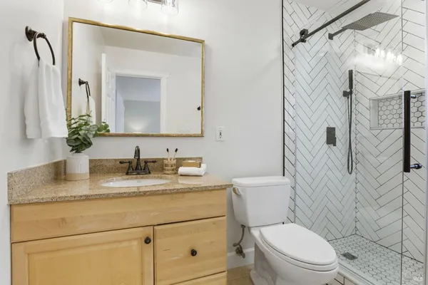 a bathroom with a granite countertop sink mirror vanity and toilet