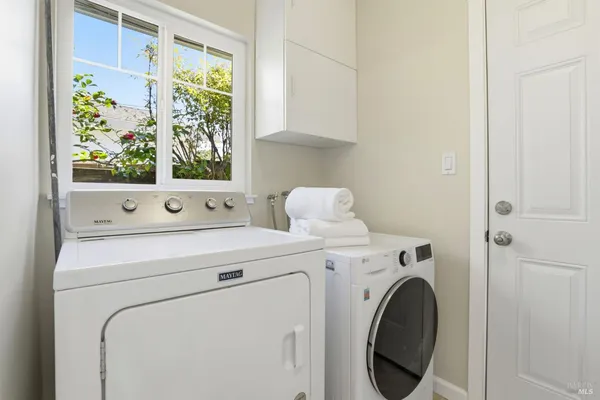 a view of washer and dryer with bathroom in the background