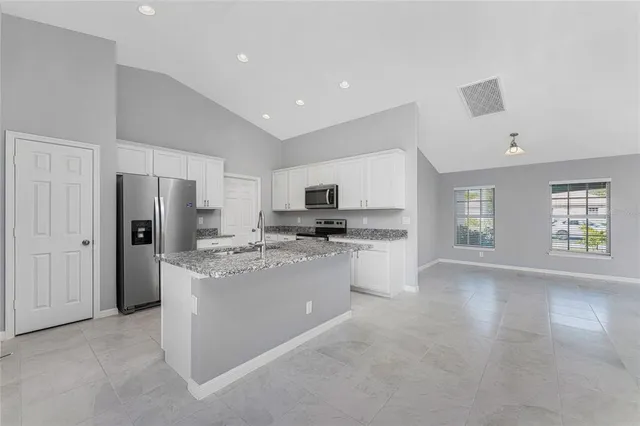 a kitchen with stainless steel appliances granite countertop a refrigerator sink and white cabinets