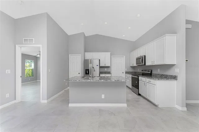 a large white kitchen with stainless steel appliances granite countertop a stove and a sink