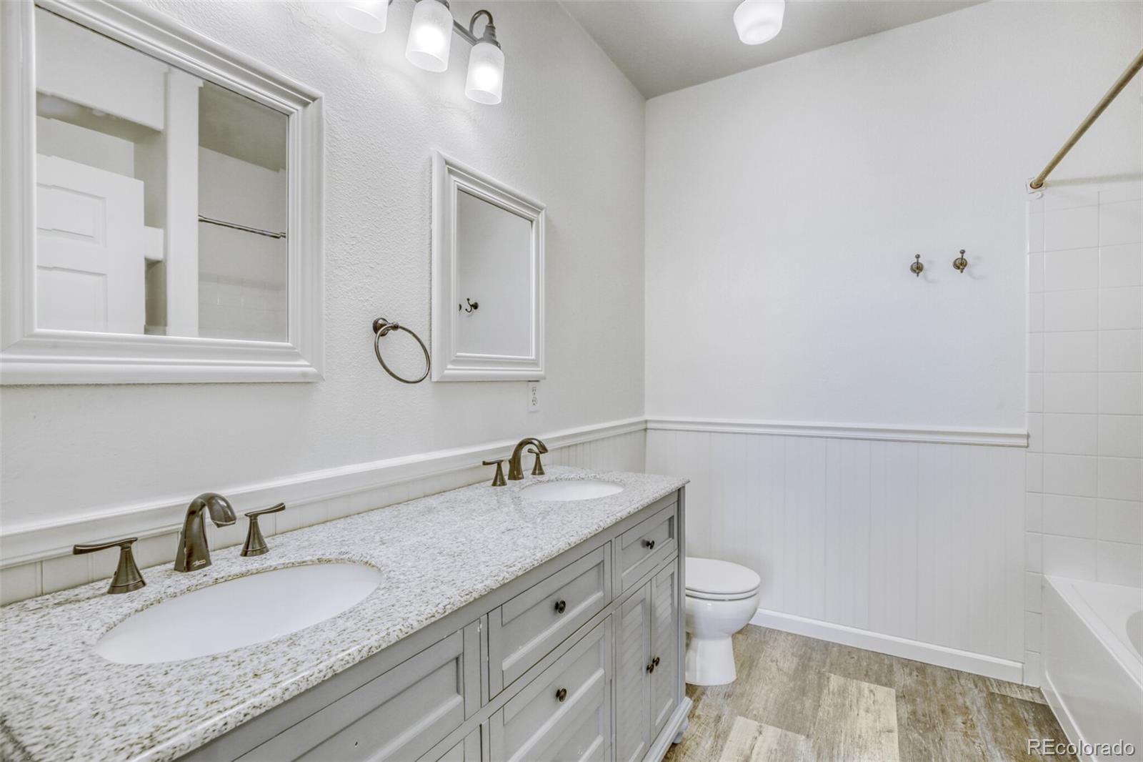 5255 Memphis Street, Unit 207 Denver, CO 80239 - Photo 17 of 21 a bathroom with a granite countertop double vanity sink a mirror and a toilet