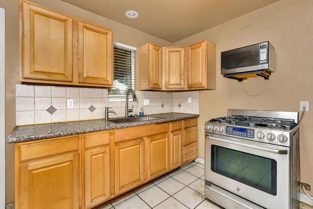 a kitchen with granite countertop a stove top oven cabinetry a sink and a window