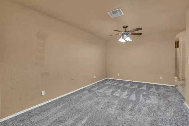 a view of an empty room with a chandelier fan