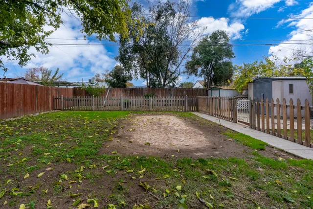a view of a backyard with a small cabin and wooden fence