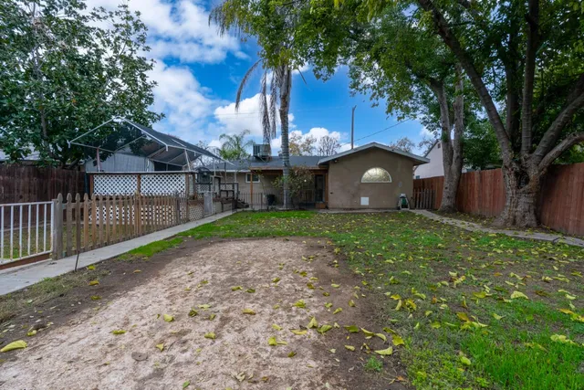 a view of a backyard with large trees and wooden fence