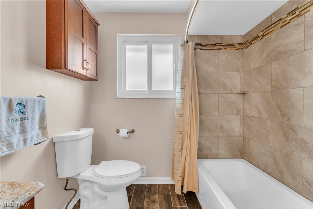 3023 Norris Avenue Cleveland, OH 44134 - Photo 25 of 41 Bathroom featuring a white tub, large format tile shower surround with decorative accent, wood-finish flooring, and a window with frosted panes
