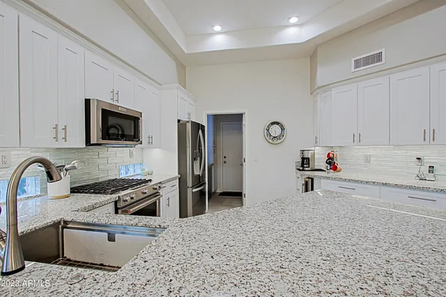 a kitchen with white cabinets and clock