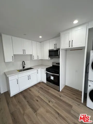 a kitchen with granite countertop a refrigerator cabinets and wooden floor
