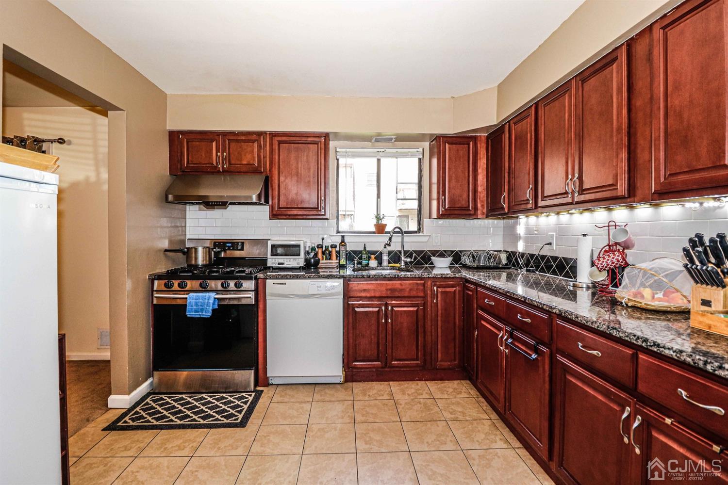 5702 Hana Road Edison, NJ 08817 - Photo 14 of 30 a kitchen with stainless steel appliances granite countertop a stove top oven a sink dishwasher and a refrigerator with wooden cabinets