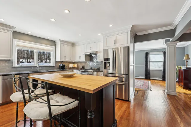 a kitchen with stainless steel appliances granite countertop a table chairs sink refrigerator and cabinets