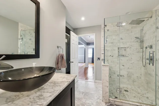 a bathroom with a granite countertop sink a mirror and shower