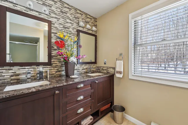 a bathroom with a granite countertop sink vanity mirror and toilet