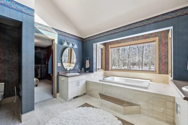 a spacious bathroom with a tub sink and mirror