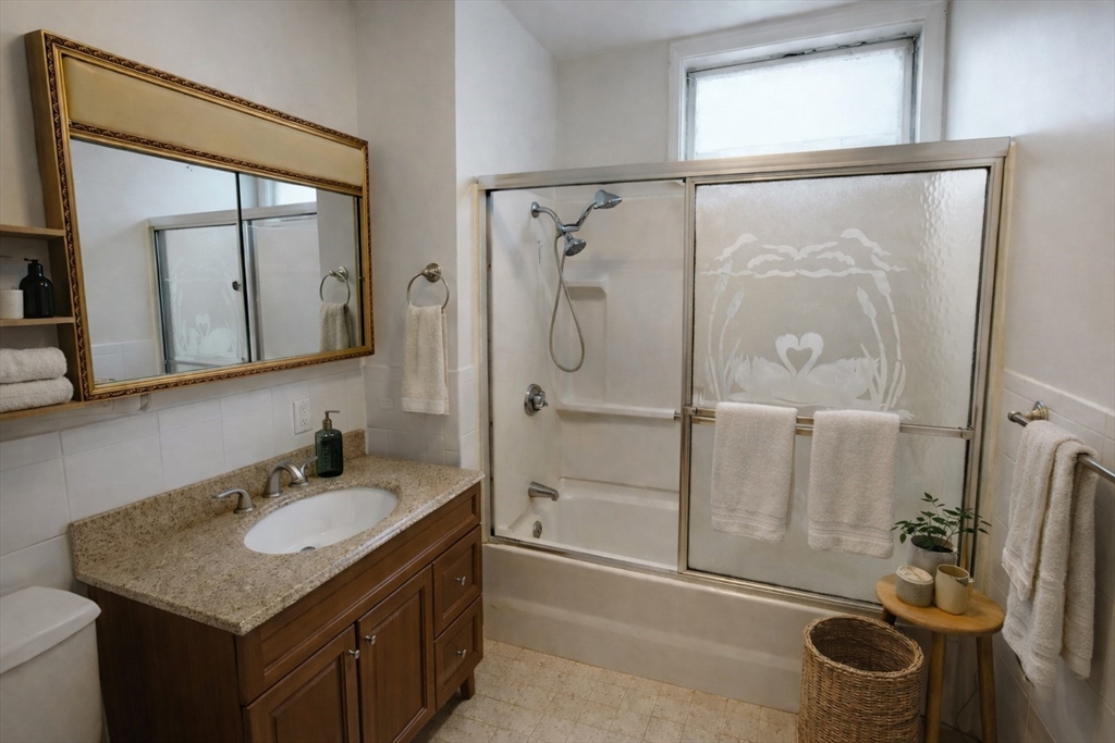 105 Walnut Street, Unit 1 Somerville, MA 02145 - Photo 3 of 14 a bathroom with a granite countertop sink a mirror and a shower