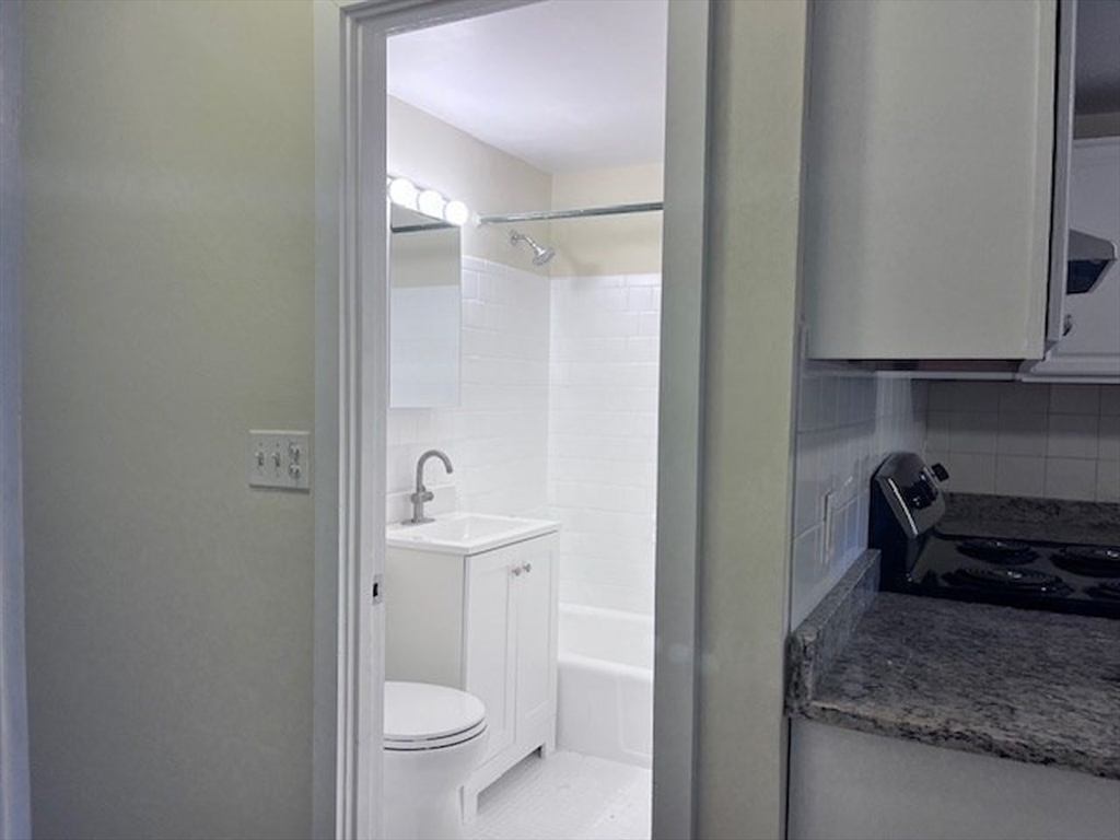 69 Nicholas Road, Unit B Framingham, MA 01701 - Photo 11 of 14 a bathroom with a granite countertop sink a toilet and a mirror
