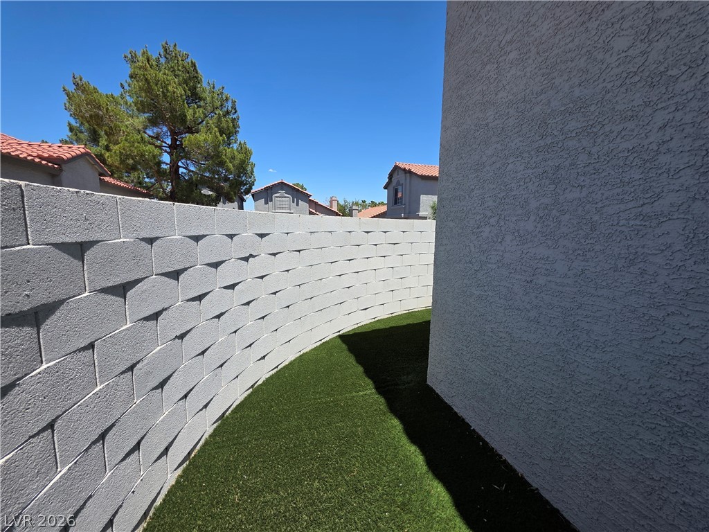 2275 Ramsgate Drive Henderson, NV 89074 - Photo 11 of 84 A neatly curved retaining wall with lush artificial turf creates a refined outdoor living space.