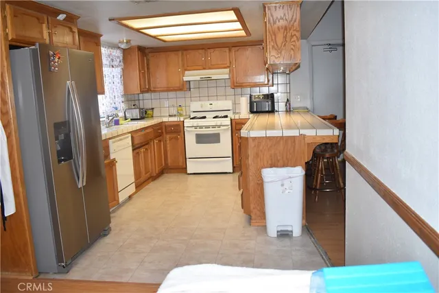 a kitchen with a refrigerator a stove top oven and cabinets