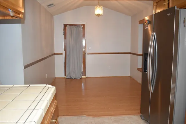 a view of a refrigerator in kitchen and an empty room