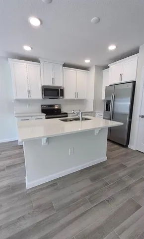 a view of kitchen with wooden floor and electronic appliances