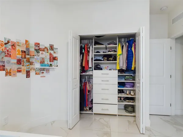 a view of walk in closet with clothes and shoes