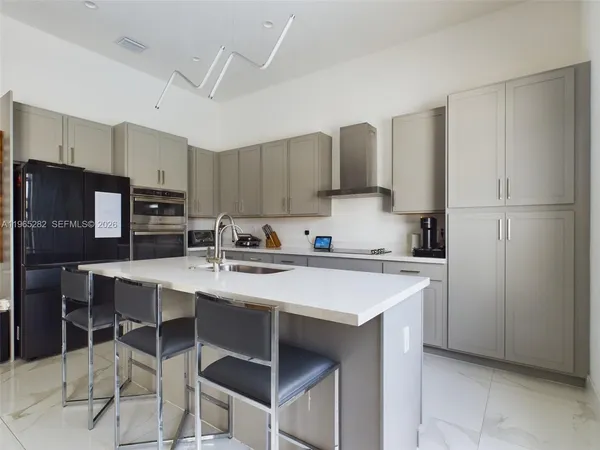 a kitchen with stainless steel appliances a sink a stove a refrigerator cabinets and chairs