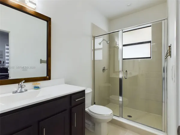 a bathroom with a shower sink vanity mirror and toilet