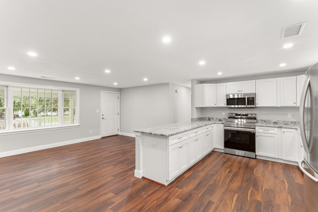 14 Fairbrook Road Framingham, MA 01701 - Photo 12 of 24 a large kitchen with stainless steel appliances granite countertop a stove top oven a sink dishwasher and white cabinets with wooden floor