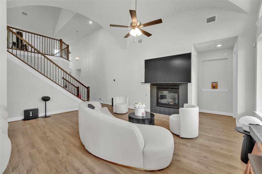 3520 Helios Lane Corinth, TX 76208 - Photo 8 of 37 Spacious living area featuring high vaulted ceilings, wood-finish flooring, and a contemporary fireplace with a dark tile surround