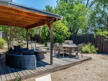 a view of a patio with table and chairs potted plants and a large tree