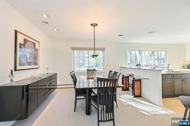a kitchen with stainless steel appliances kitchen island granite countertop a stove a refrigerator a sink a dining table and chairs with wooden floor