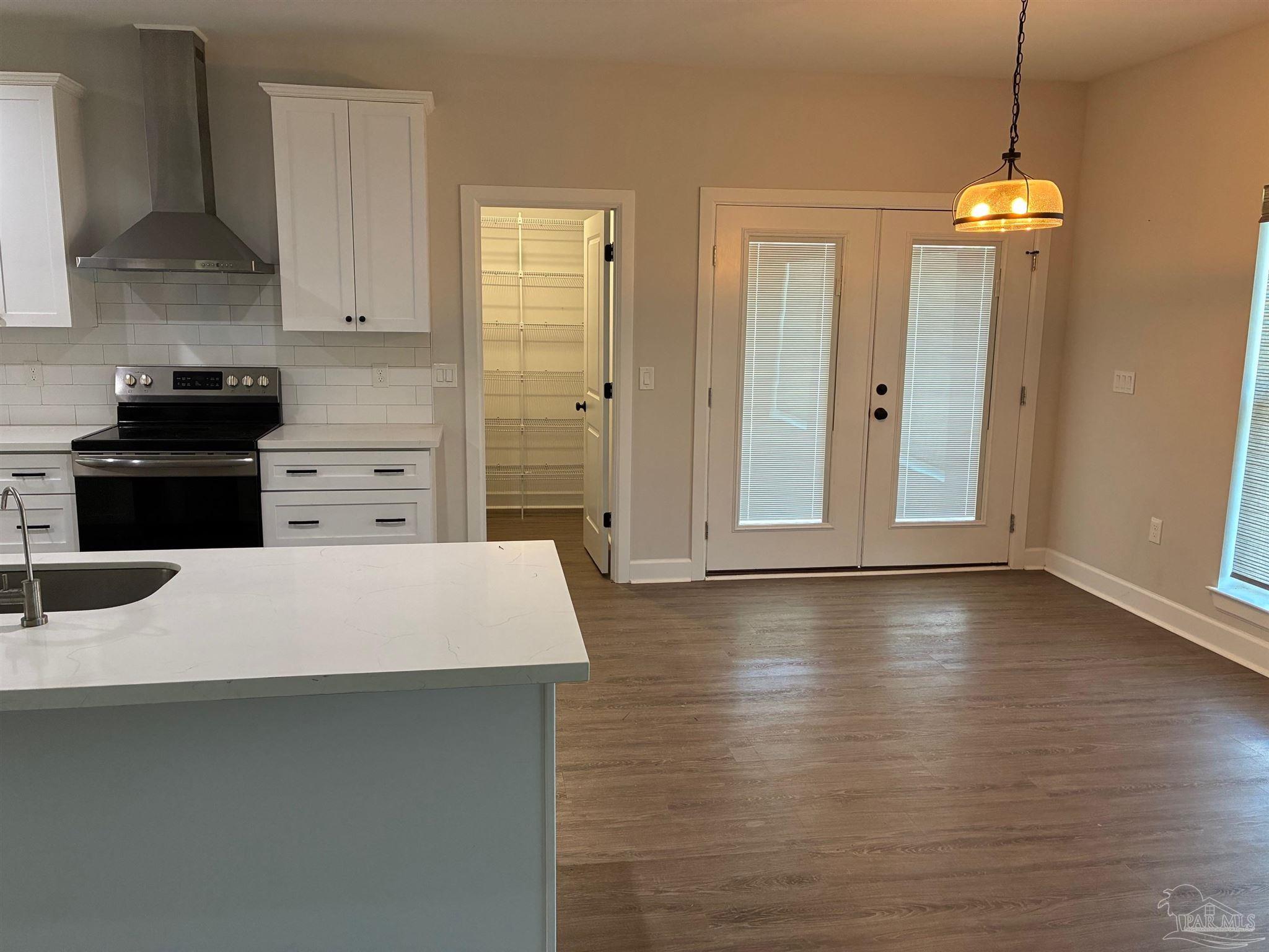 4090 Manchester Court Pace, FL 32571 - Photo 4 of 33 a large white kitchen with stainless steel appliances a stove a refrigerator a sink a microwave oven and white cabinets with wooden floor