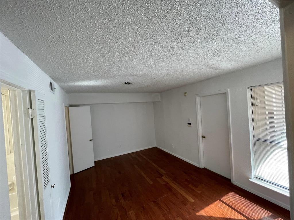 9811 Walnut Street, Unit F207 Dallas, TX 75243 - Photo 5 of 12 Unfurnished room with dark wood finished floors and a textured ceiling