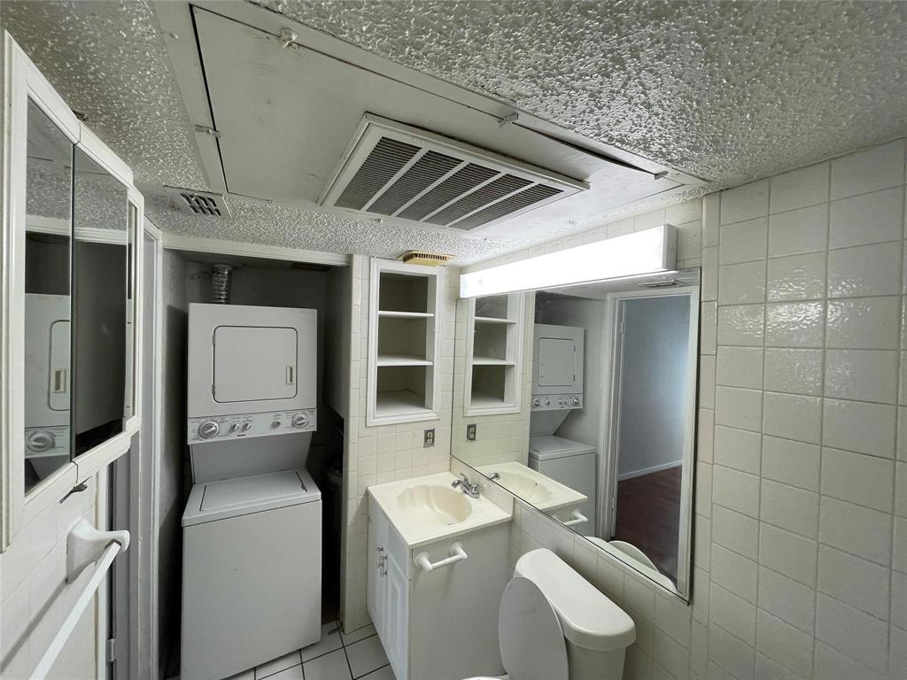 9811 Walnut Street, Unit F207 Dallas, TX 75243 - Photo 6 of 12 Half bathroom featuring stacked washer and dryer, vanity, tile walls, and light tile patterned floors