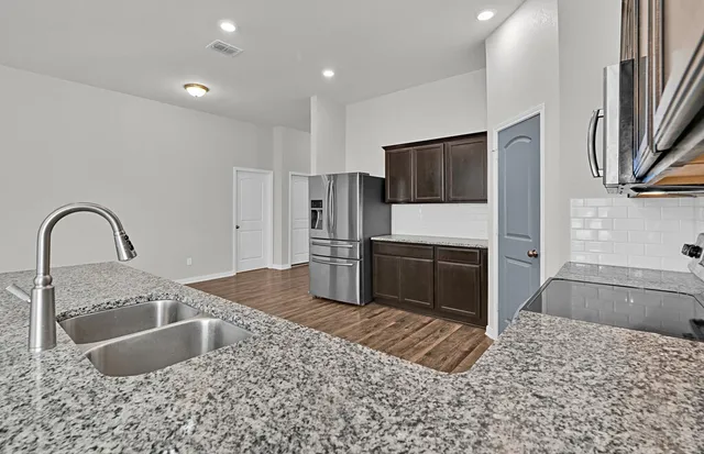 a kitchen with stainless steel appliances granite countertop a sink and a stove top oven with wooden floor