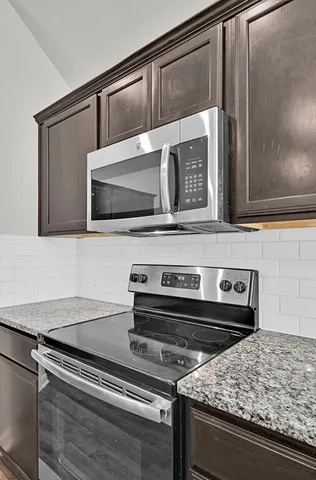 a kitchen with granite countertop a stove and a microwave