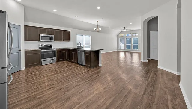 a large kitchen with stainless steel appliances kitchen island granite countertop a large counter top and wooden floors