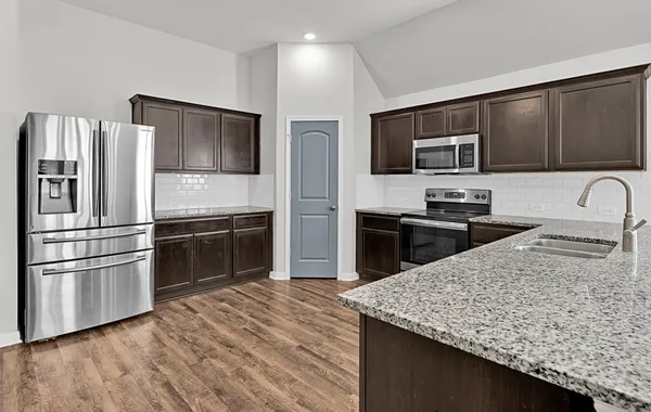a kitchen with stainless steel appliances kitchen island granite countertop a refrigerator and a stove top oven