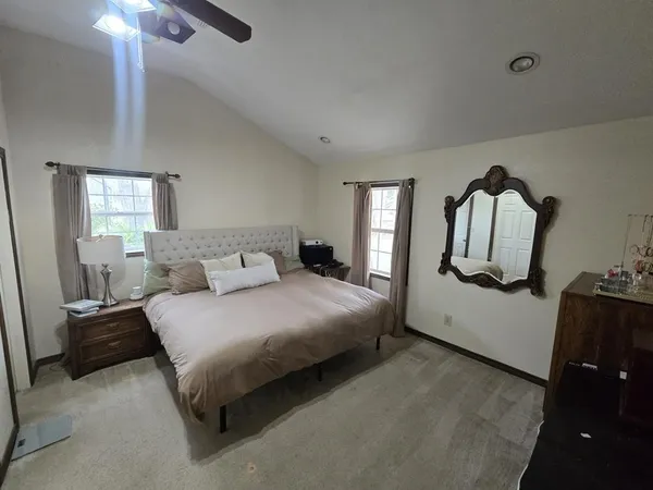 a bedroom with a bed mirror on dresser and a chandelier
