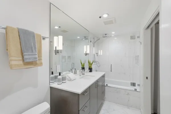 a bathroom with a bathtub shower sink vanity and a mirror