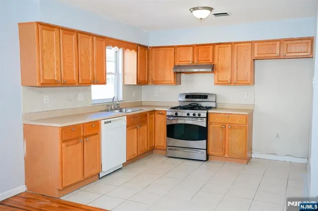 a kitchen with granite countertop stainless steel appliances a stove sink and cabinets