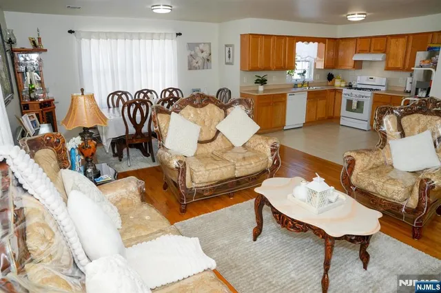 a living room with furniture a rug kitchen view and a large window