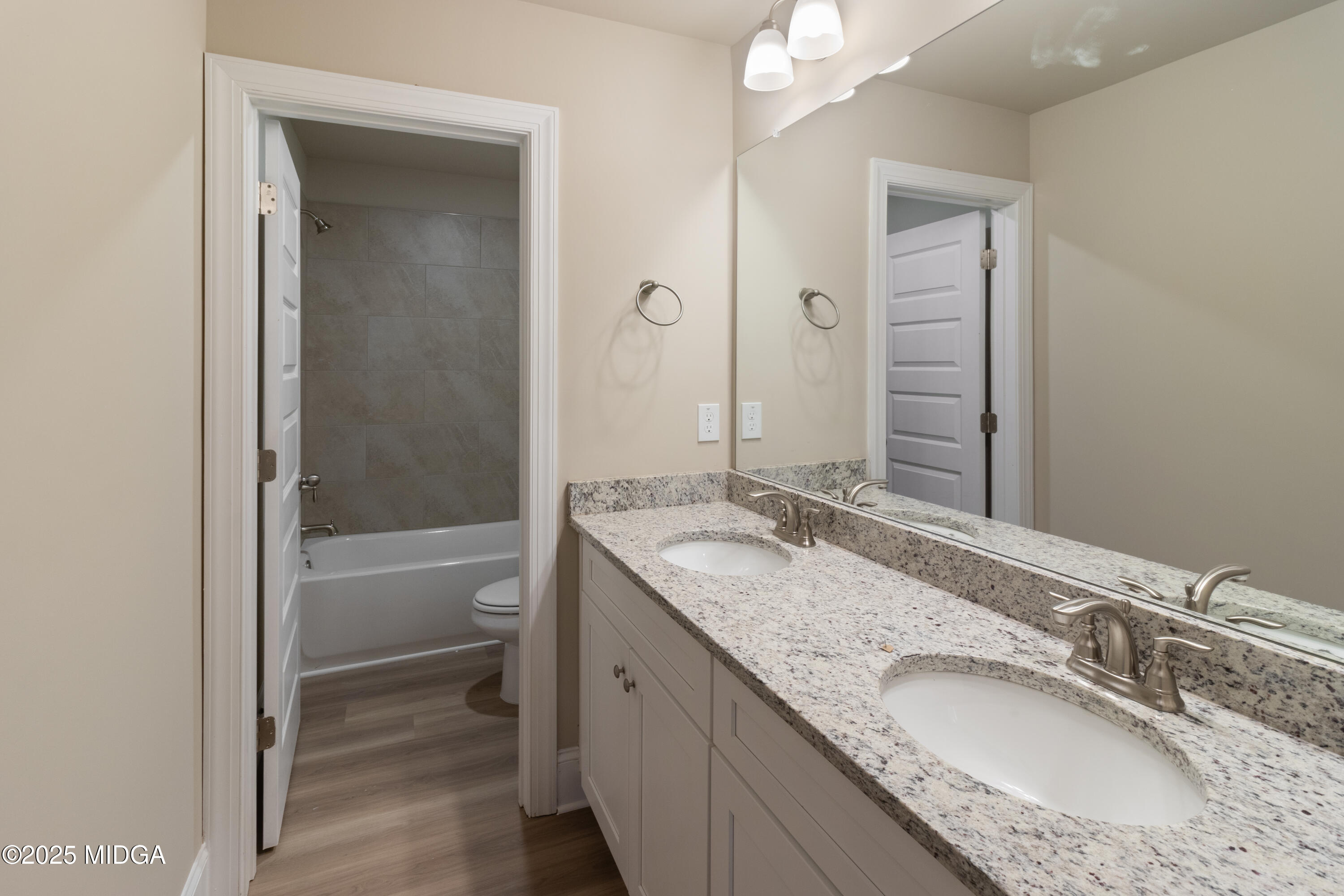 697 Giles Road Forsyth, GA 31029 - Photo 24 of 27 a bathroom with a granite countertop double vanity sink and mirror with bathtub
