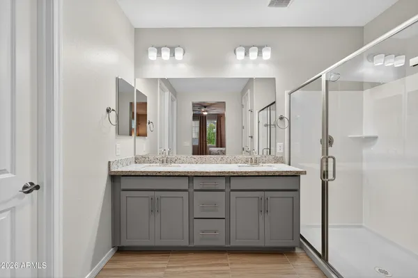 a bathroom with a granite countertop sink two mirror and a shower