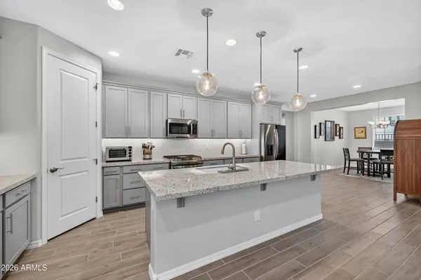 a large white kitchen with lots of counter space a sink appliances and cabinets