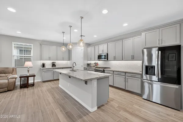 a large kitchen with stainless steel appliances a large counter top a sink a stove and a refrigerator