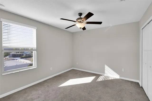 an empty room with a window and a fan